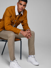 رجل يجلس مرتديًا البنطلون البيج مع سترة برتقالية