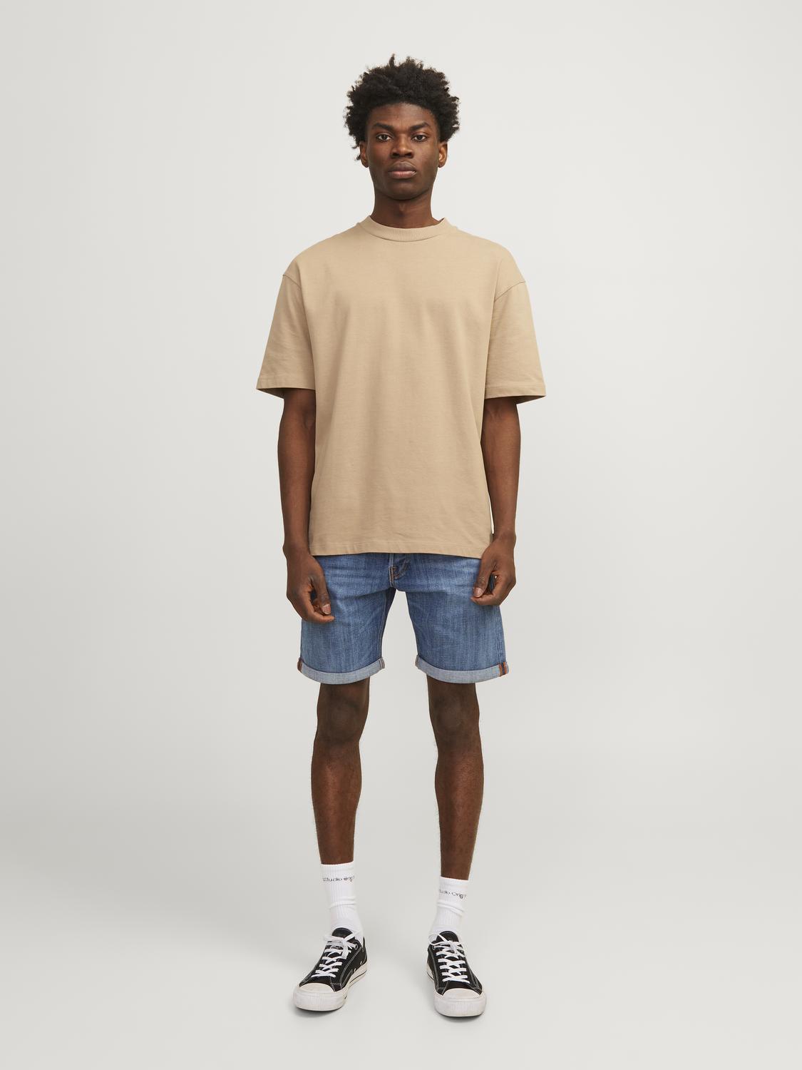 رجل واقف من الأمام يرتدي الشورت مع تيشيرت بيج.