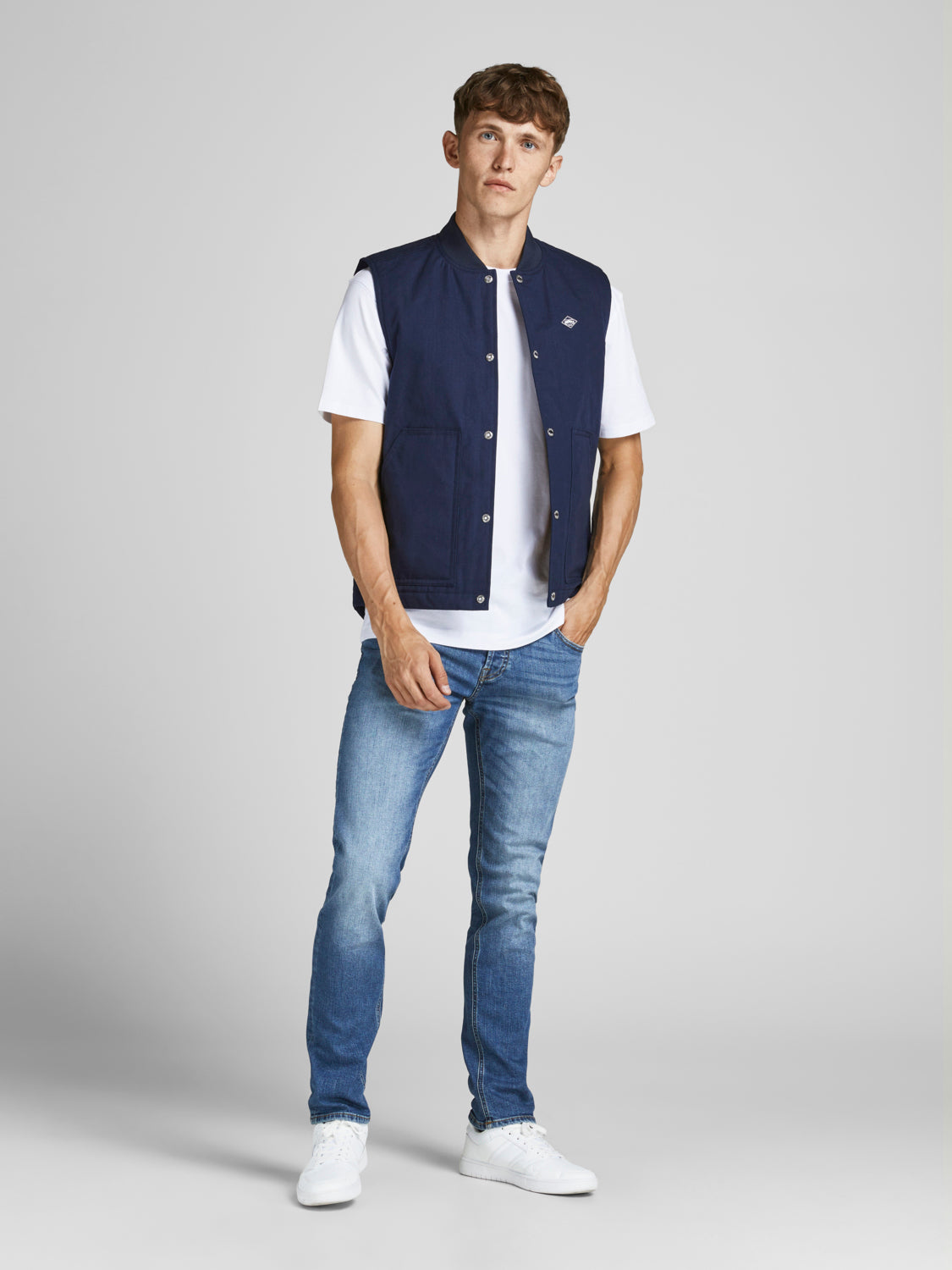 رجل يرتدي البنطلون الجينز السكيني الأزرق ويقف بوضعية مريحة