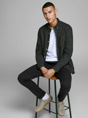 رجل يجلس مرتديًا البنطلون الأسود بطريقة عصرية