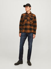 موديل يرتدي البنطلون الجينز الأزرق الغامق مع قميص كاجوال بني وأسود