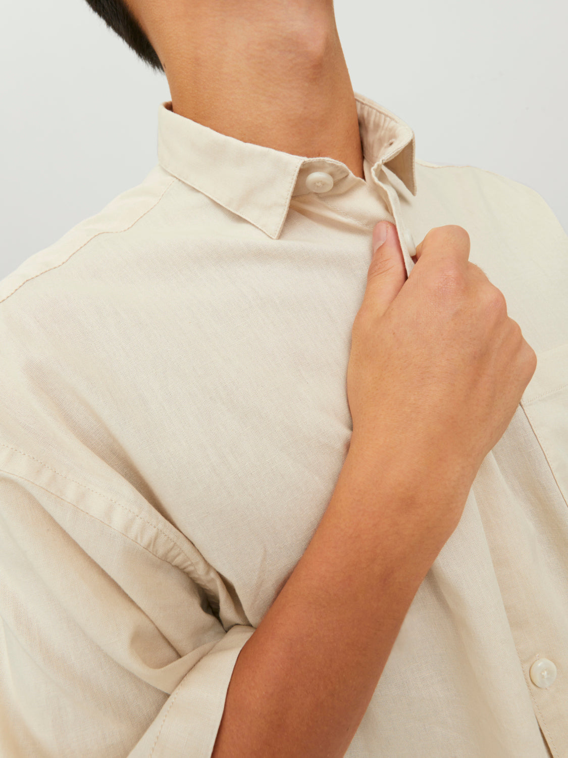 لقطة مقربة تظهر تفاصيل ياقة قميص نص كم رجالي بيج فاتح وأزراره