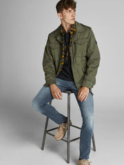 موديل يرتدي بنطلون جينز رجالي أزرق داكن مع جاكيت أخضر